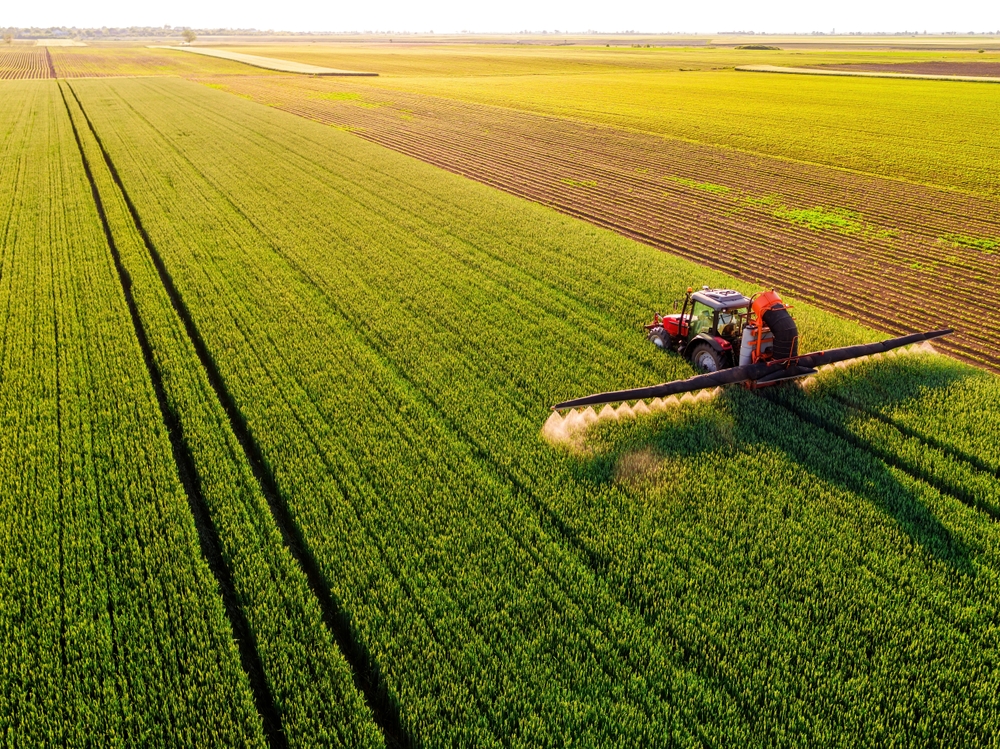 Drone,Shot,Of,A,Tractor,Spraying,In,Lush,Green,Wheat